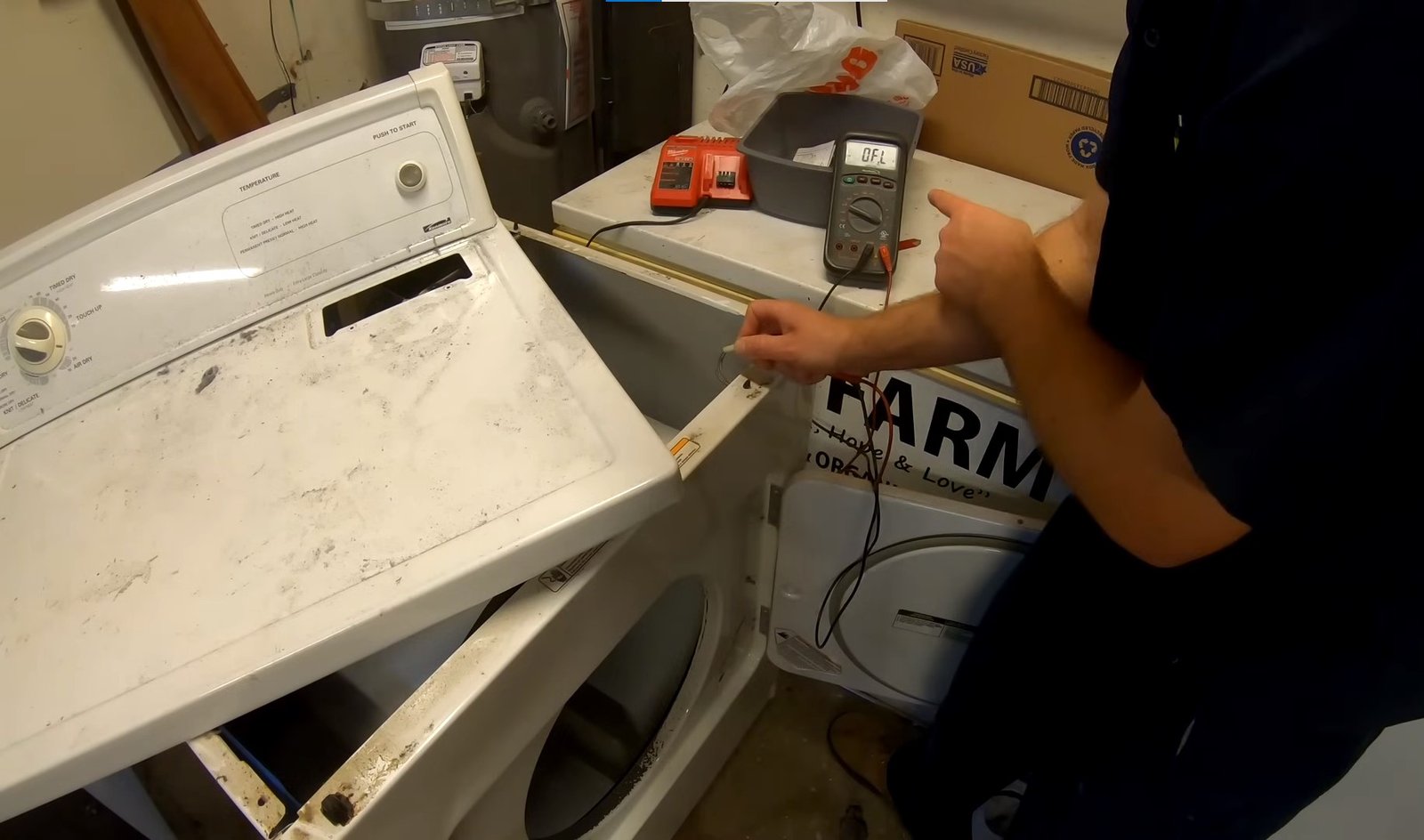 Technician testing the wiring of a Kenmore dryer with a multimeter